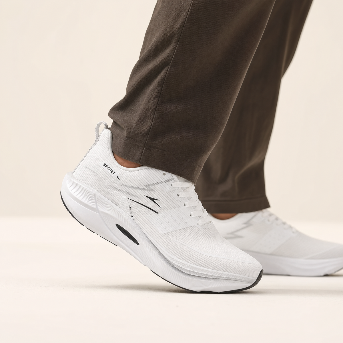 White air-cushion running shoe worn by a runner, cream studio backdrop